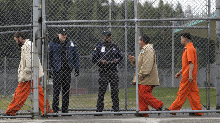 Inmates walk past correctional officers at the Washington Corrections Center in Shelton, Wash., in 2011. Gov. Jay Inslee said Tuesday that more than 3,000 prisoners in Washington have been mistakenly released early since 2002 because of an error by the state's Department of Corrections.