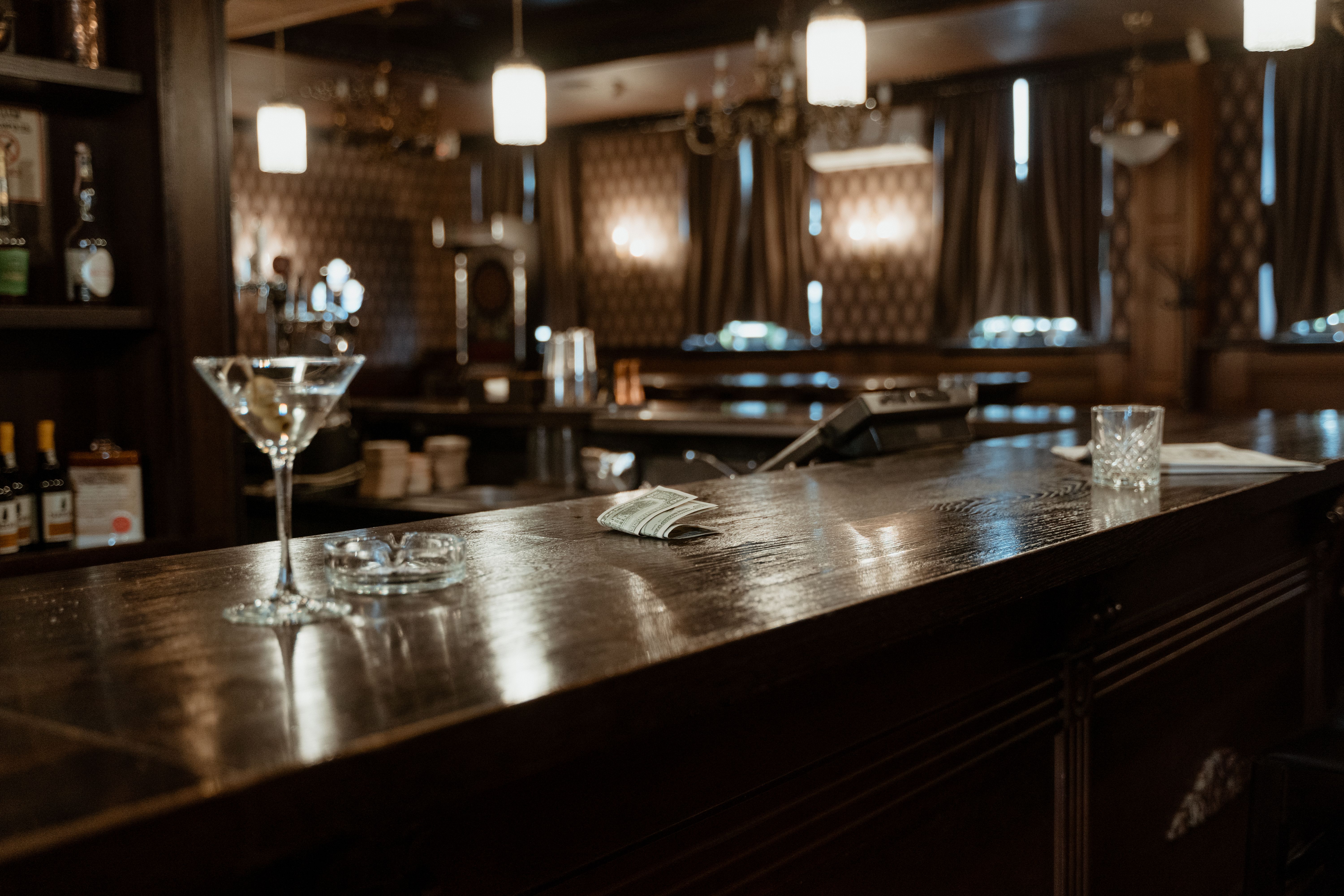 Moody cocktail bar counter with glassware and an inviting upscale atmosphere.