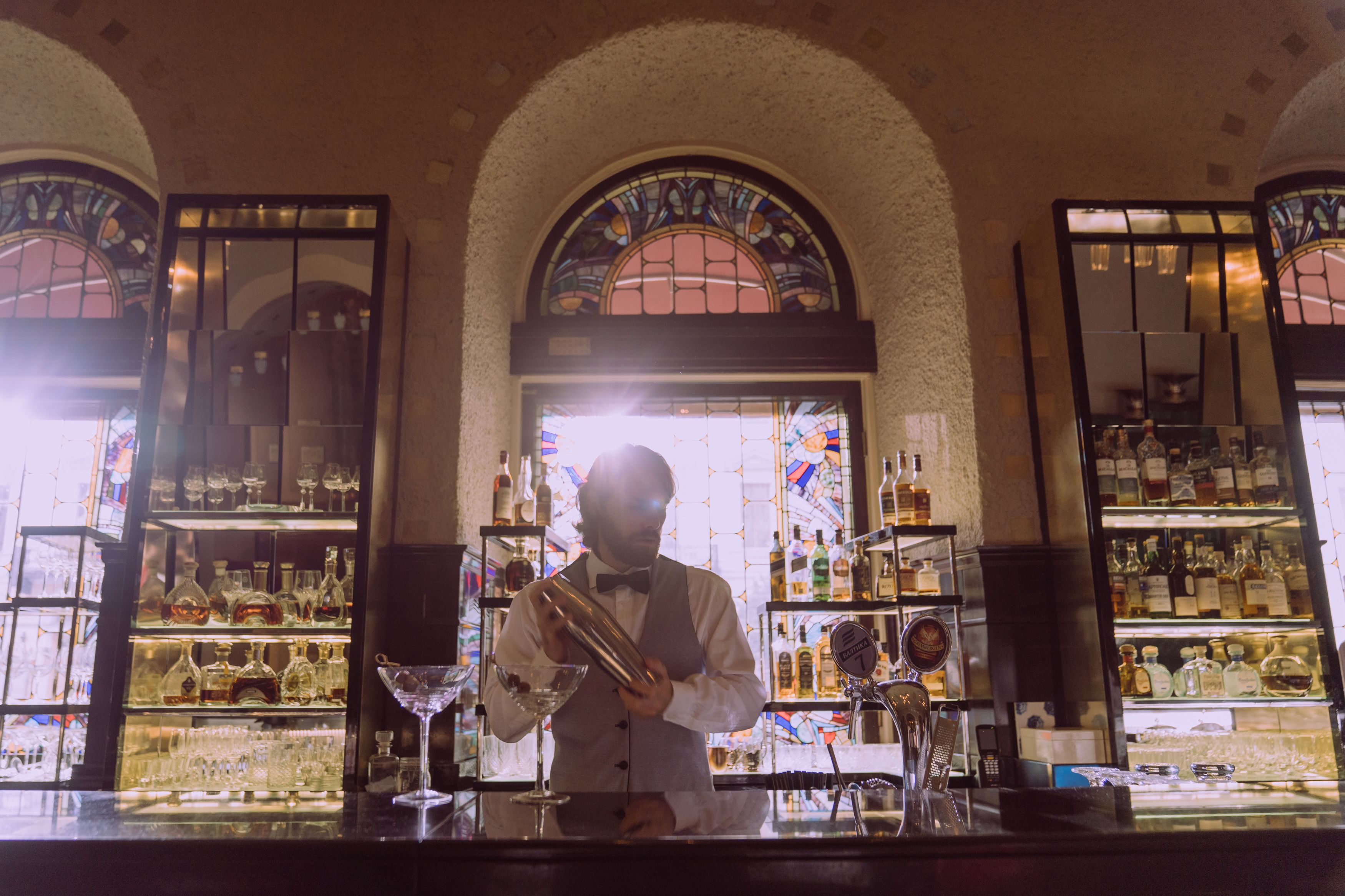 Bartender preparing cocktails in an elegant, warmly lit bar.